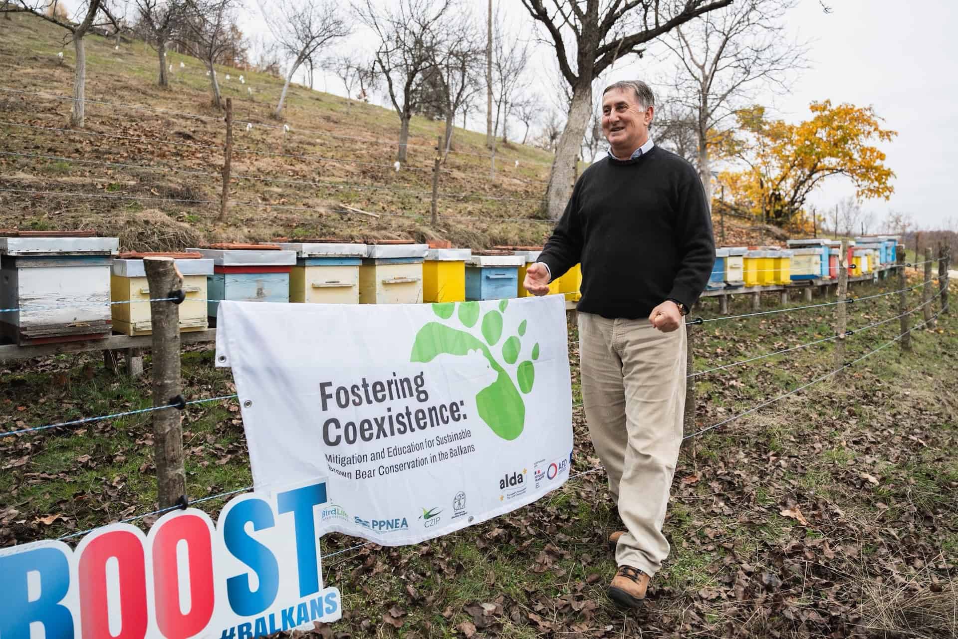 A satisfied man near the electric fencing around his beehives