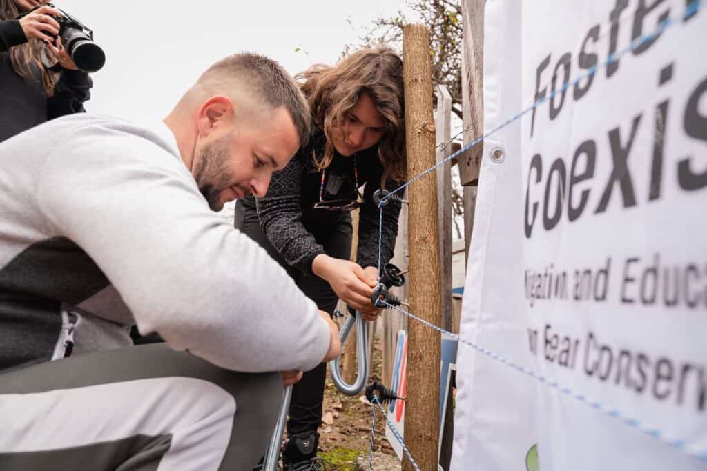 A man and a woman working on an electric fence