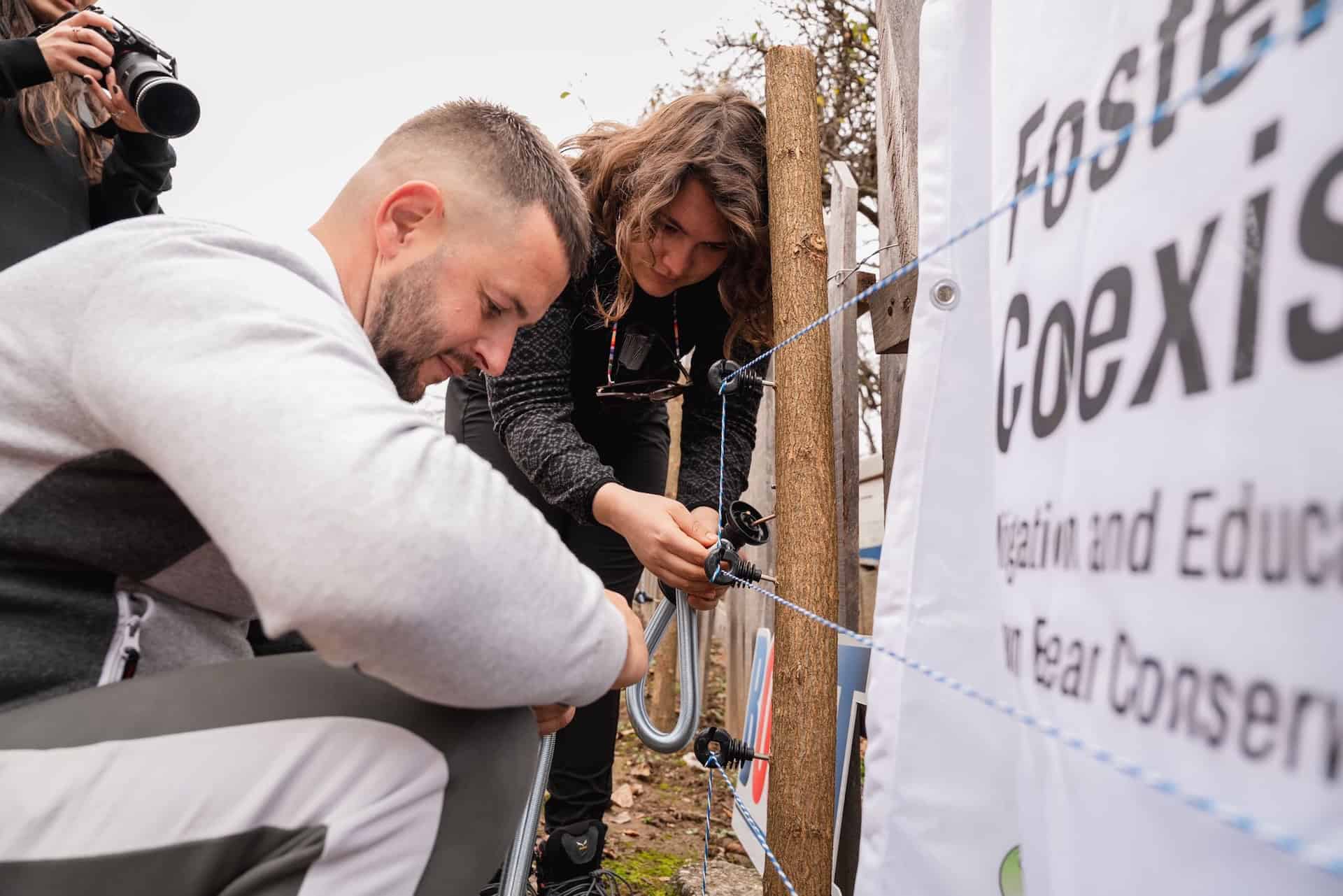 A man and a woman working on an electric fence